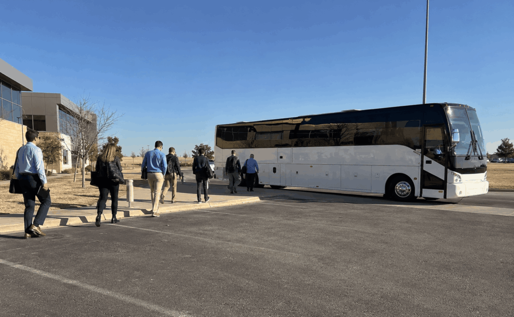 modern charter bus picking up employees outside an abilene office for a corporate shuttle route