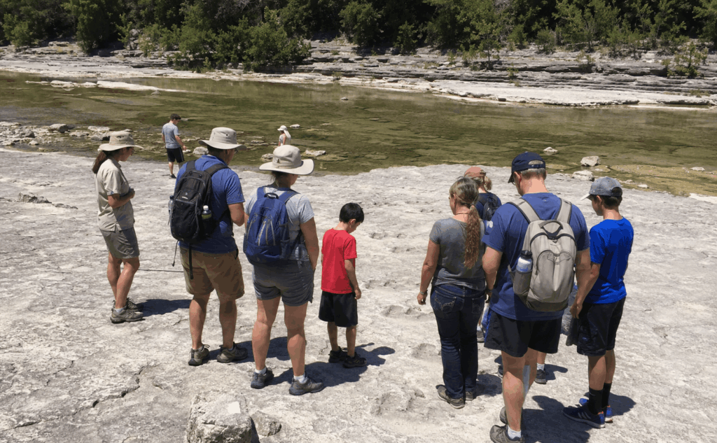 group viewing dinosaur tracks along the paluxy river at dinosaur valley state park in glen rose texas