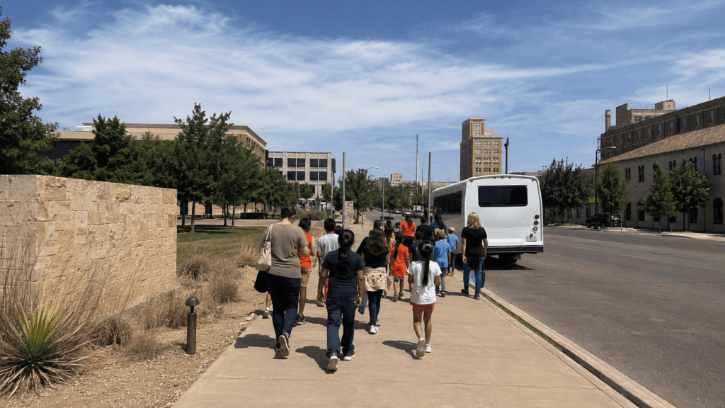 students and chaperones walking through downtown abilene after a frontier texas visit with their charter bus nearby