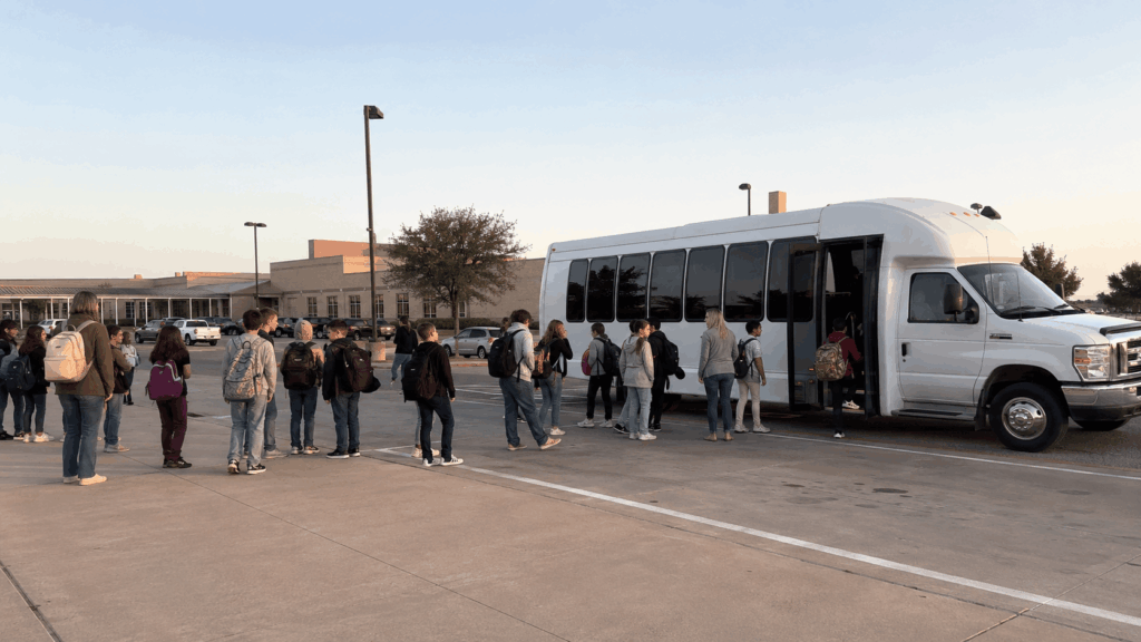 minibus loading students and chaperones at an abilene school parking lot before a frontier texas field trip